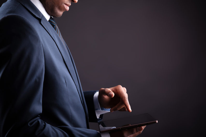 Businessman holding digital tablet on black background