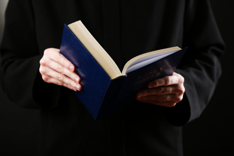 Priest reading from the holy bible, close up