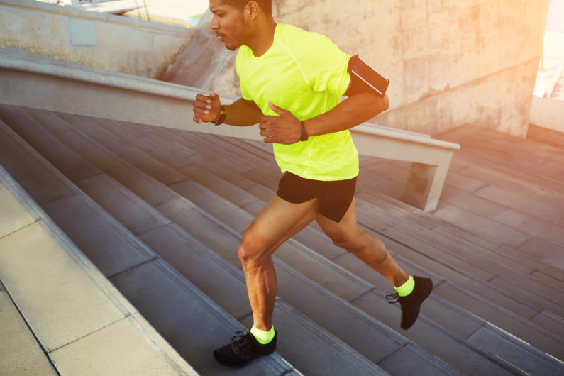 Dark-skinned athlete running up a flight of stairs with speed